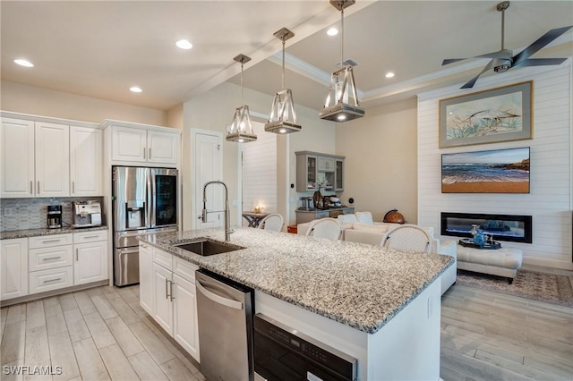 9292 Cayman Dr, Naples, FL 34114 - kitchen featuring stainless steel appliances, a sink, a large fireplace, white cabinetry, and ornamental molding