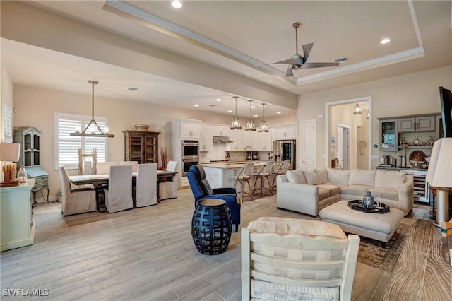 9292 Cayman Dr, Naples, FL 34114 - living room featuring a tray ceiling, a ceiling fan, a chandelier, light wood-style flooring, and recessed lighting