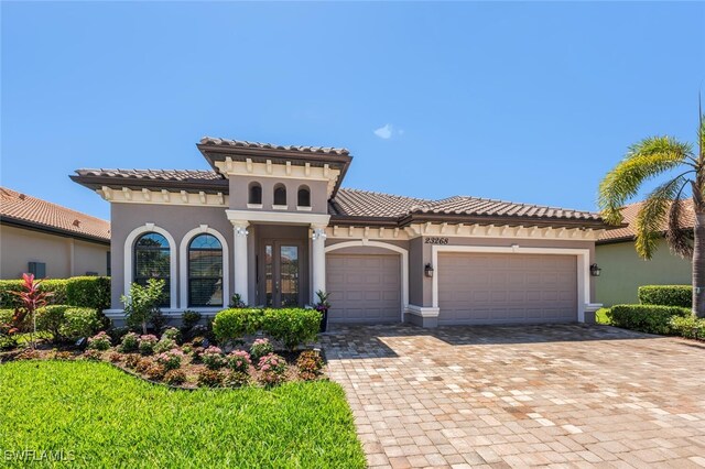 23268 Sanabria Loop, Bonita Springs, FL 34135 - mediterranean / spanish-style house with stucco siding, a tiled roof, a garage, and decorative driveway