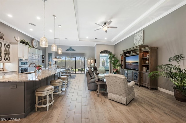 23268 Sanabria Loop, Bonita Springs, FL 34135 - living area featuring a raised ceiling, ceiling fan, light wood finished floors, and ornamental molding