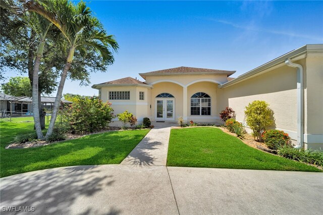 2010 SE 13th Ter, Cape Coral, FL 33990 - mediterranean / spanish-style home with french doors, stucco siding, and a front yard