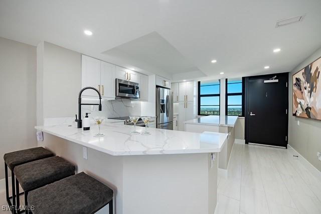380 Seaview Ct Unit 1704, Marco Island, FL 34145 - kitchen featuring appliances with stainless steel finishes, a center island, recessed lighting, white cabinetry, and a peninsula