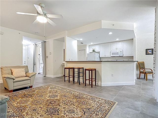 1732 Tarpon Bay Dr S Unit 101, Naples, FL 34119 - kitchen with white appliances, ceiling fan, dark countertops, white cabinets, and open floor plan