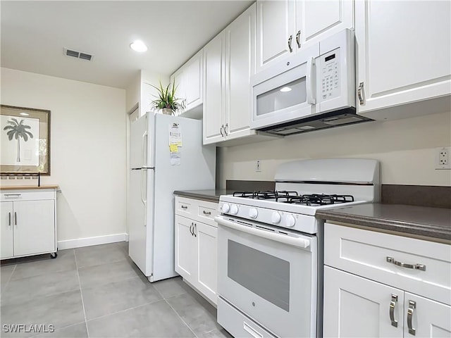 1732 Tarpon Bay Dr S Unit 101, Naples, FL 34119 - kitchen with white appliances, dark countertops, white cabinetry, light tile patterned flooring, and baseboards