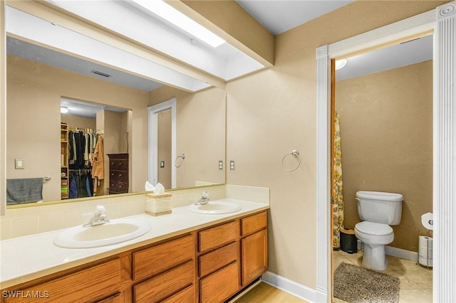 7269 Heaven Ln, Fort Myers, FL 33908 - full bathroom featuring double vanity, toilet, a walk in closet, tile patterned floors, and baseboards