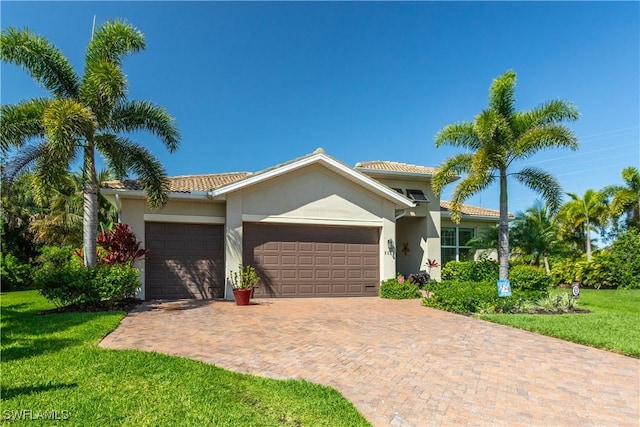 8651 Colony Trace Dr, Fort Myers, FL 33908 - mediterranean / spanish-style house with an attached garage, a front lawn, stucco siding, a tiled roof, and decorative driveway