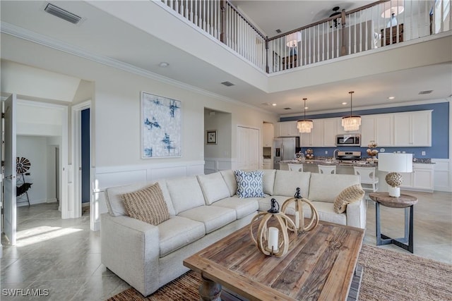 10871 Rose Quartz Ln, North Fort Myers, FL 33917 - living room with ornamental molding, a towering ceiling, a decorative wall, wainscoting, and recessed lighting