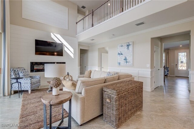 10871 Rose Quartz Ln, North Fort Myers, FL 33917 - living area with a towering ceiling, ornamental molding, a decorative wall, light tile patterned floors, and a wainscoted wall