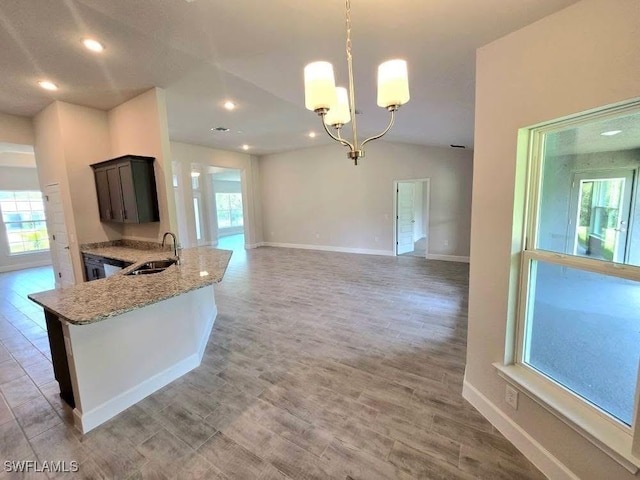 2201 Como St, Port Charlotte, FL 33948 - kitchen featuring a chandelier, a sink, light stone counters, baseboards, and decorative light fixtures