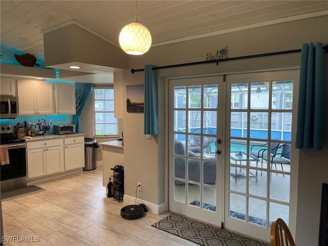 17133 Phlox Dr, Fort Myers, FL 33967 - kitchen with stainless steel appliances, white cabinets, vaulted ceiling, wood ceiling, and french doors