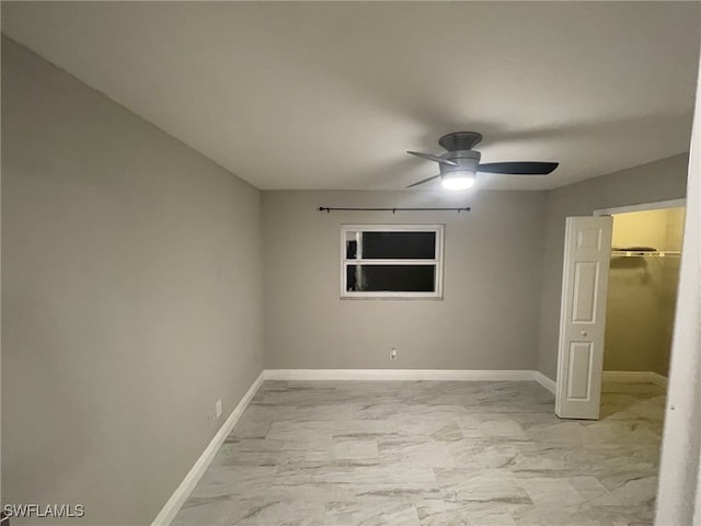 17133 Phlox Dr, Fort Myers, FL 33967 - unfurnished bedroom with baseboards, light marble finish flooring, a ceiling fan, and a walk in closet