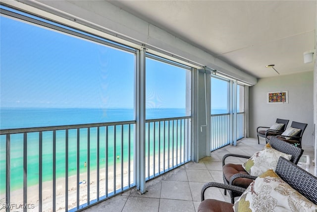sunroom featuring view of water and beach