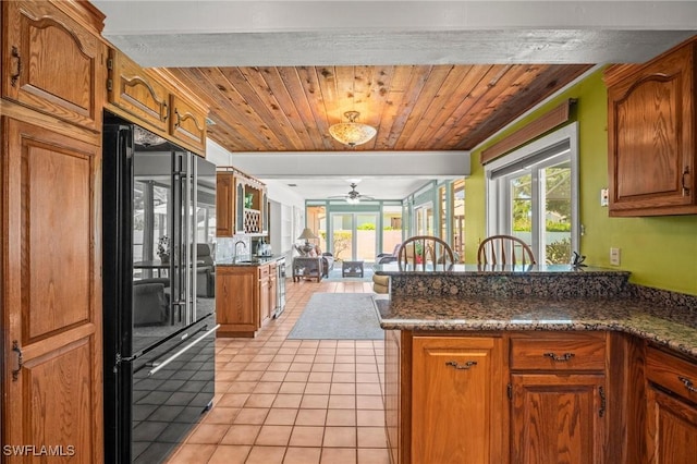 1263 Caloosa Dr, Fort Myers, FL 33901 - kitchen with freestanding refrigerator, a ceiling fan, a peninsula, light tile patterned flooring, and brown cabinets