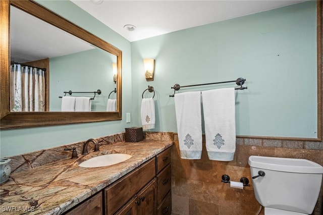 1263 Caloosa Dr, Fort Myers, FL 33901 - bathroom with toilet, vanity, a wainscoted wall, and tile walls