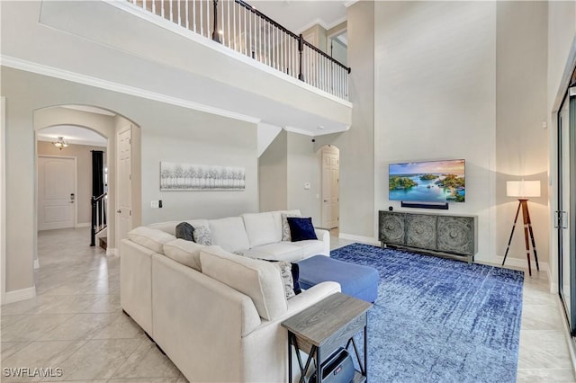 2102 Antigua Ln, Naples, FL 34120 - living room featuring arched walkways, crown molding, a towering ceiling, baseboards, and light tile patterned floors