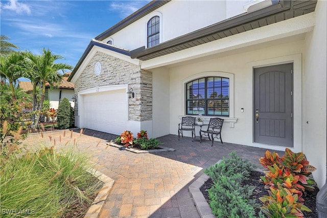 2102 Antigua Ln, Naples, FL 34120 - property entrance with stucco siding, stone siding, covered porch, a garage, and driveway
