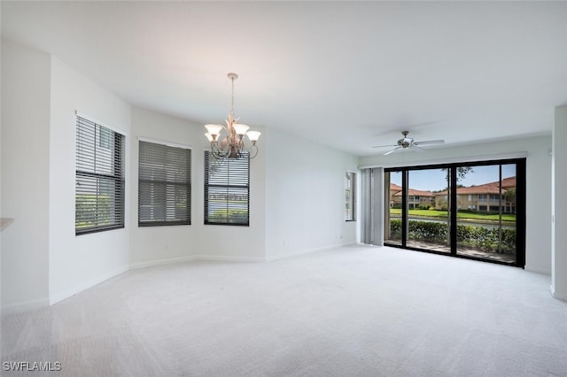 carpeted spare room with a chandelier, baseboards, and a ceiling fan