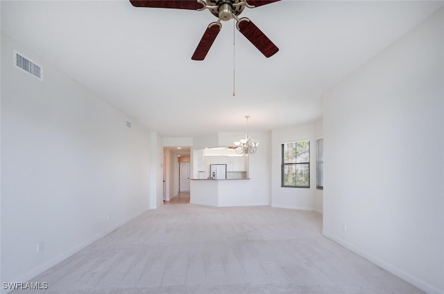 unfurnished living room with a chandelier, ceiling fan, light carpet, and baseboards