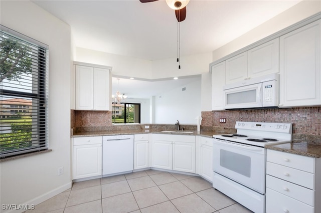 kitchen with white appliances, a sink, backsplash, light tile patterned floors, and white cabinets