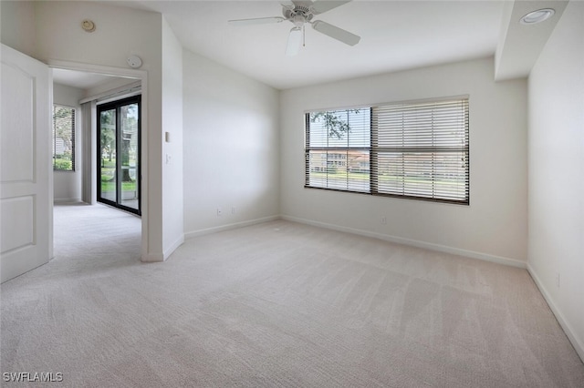 unfurnished room featuring light carpet, baseboards, ceiling fan, and a smoke detector