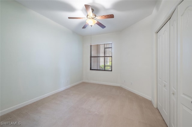 unfurnished bedroom featuring light colored carpet, a closet, baseboards, and ceiling fan