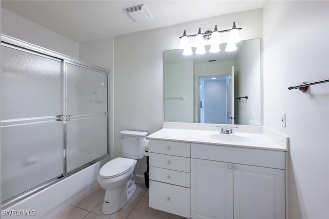 bathroom with toilet, tile patterned flooring, vanity, and bath / shower combo with glass door