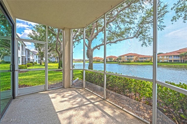 unfurnished sunroom featuring a water view, a residential view, and plenty of natural light
