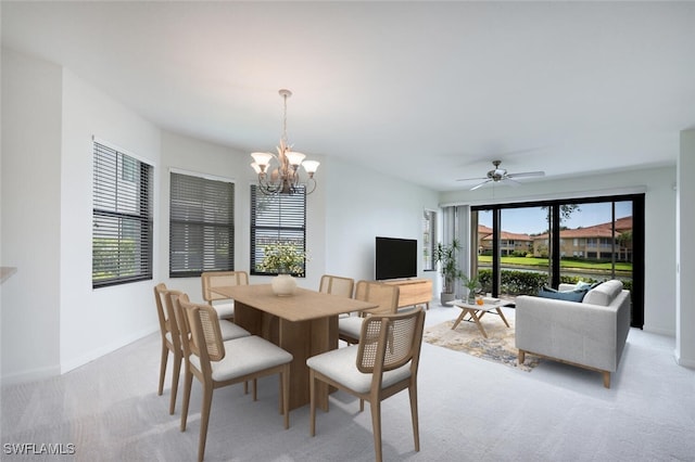 dining room with a chandelier, light carpet, a ceiling fan, and baseboards