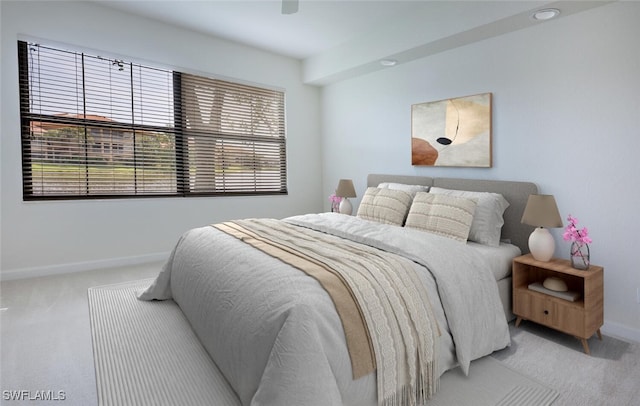 bedroom with light carpet, multiple windows, and baseboards