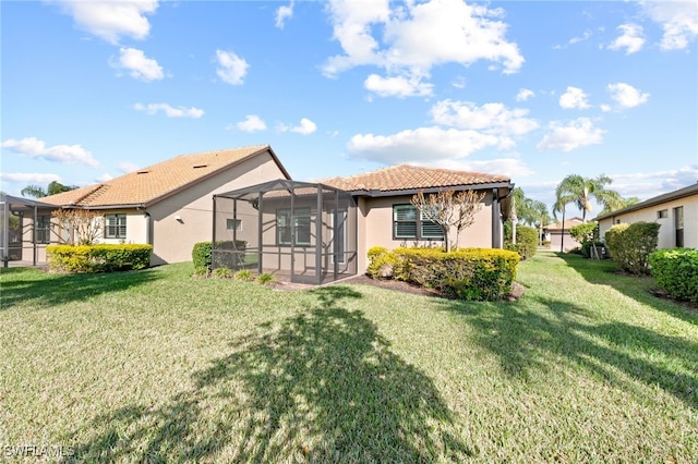 10947 Clarendon St, Fort Myers, FL 33913 - back of property featuring a lawn, stucco siding, a tiled roof, and glass enclosure