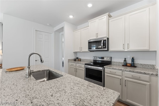 16523 Crescent Beach Way, Bonita Springs, FL 34135 - kitchen featuring appliances with stainless steel finishes, a sink, light stone counters, white cabinets, and recessed lighting