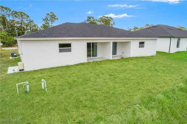 876 Apartment St E, Lehigh Acres, FL 33974 - rear view of house featuring a lawn, stucco siding, a shingled roof, and a patio