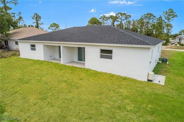 876 Apartment St E, Lehigh Acres, FL 33974 - back of property featuring a shingled roof, a yard, a patio, and stucco siding