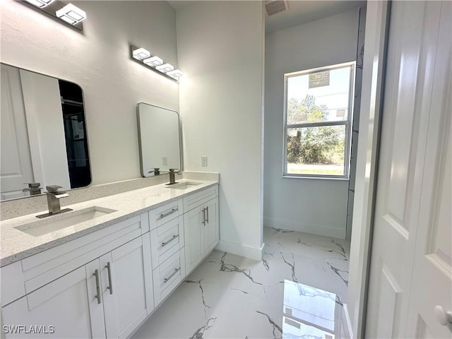 bathroom with double vanity, marble finish flooring, and baseboards