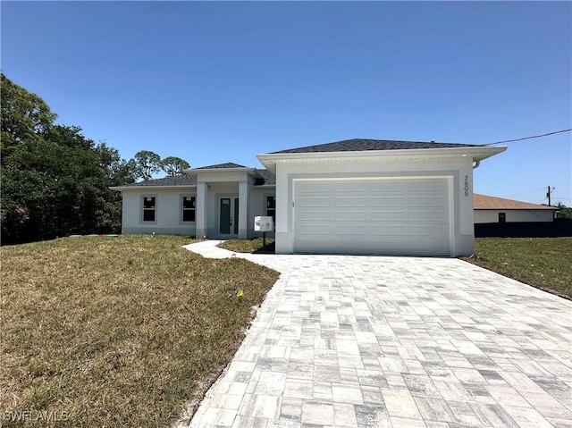 prairie-style house featuring decorative driveway, a front yard, a garage, and stucco siding