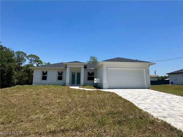 view of front of home featuring french doors, stucco siding, an attached garage, a front lawn, and decorative driveway