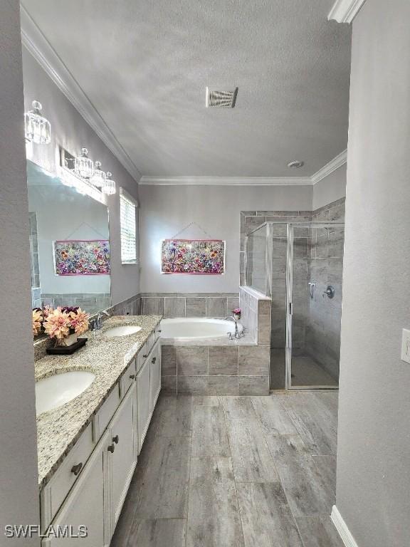 16006 Mistflower Dr, Alva, FL 33920 - bathroom featuring a garden tub, double vanity, wood finished floors, a shower stall, and ornamental molding