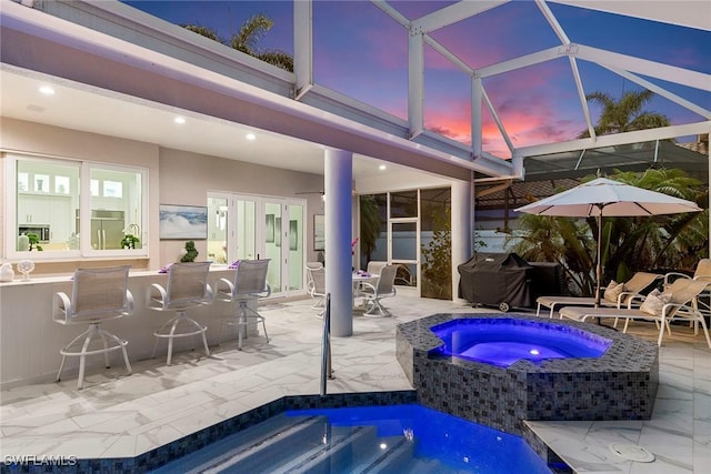 287 Meadowlark Ct, Marco Island, FL 34145 - pool at dusk with an in-ground hot tub, a patio area, an outdoor pool, grilling area, and glass enclosure