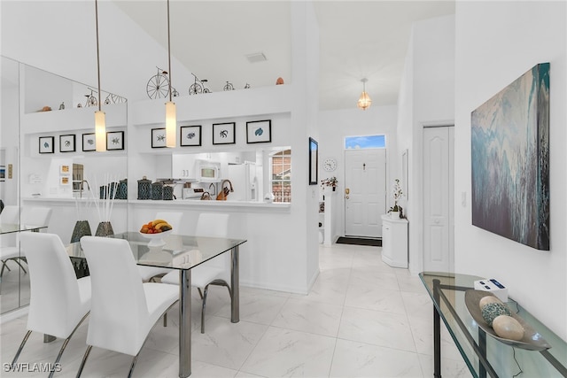 154 Newport Dr Unit 1307, Naples, FL 34114 - dining space with a high ceiling, marble look tiles, and baseboards