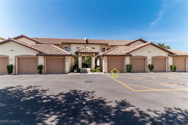 154 Newport Dr Unit 1307, Naples, FL 34114 - view of front of house featuring stucco siding, community garages, and a tiled roof