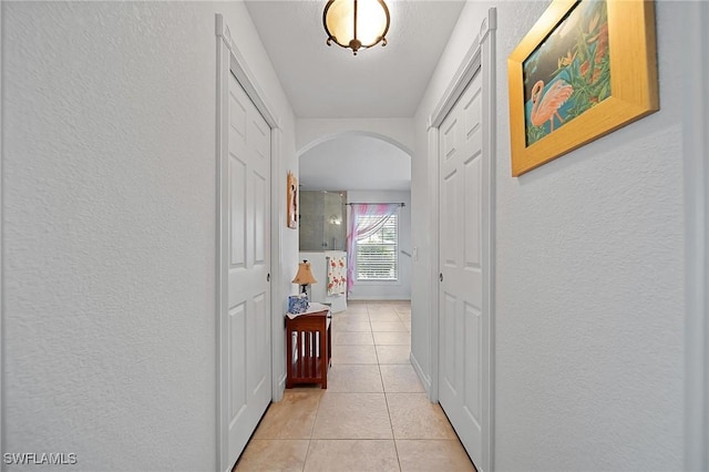 134 Dartmouth Dr NW, Port Charlotte, FL 33952 - hallway featuring arched walkways, a textured wall, and light tile patterned floors