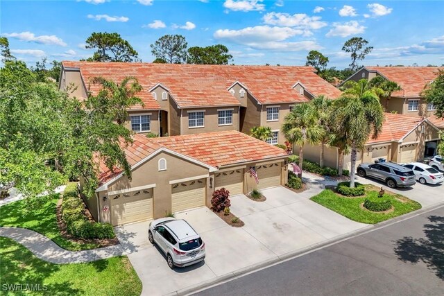 20101 Seagrove St Unit 702, Estero, FL 33928 - view of front of property featuring stucco siding, driveway, a tiled roof, and a garage