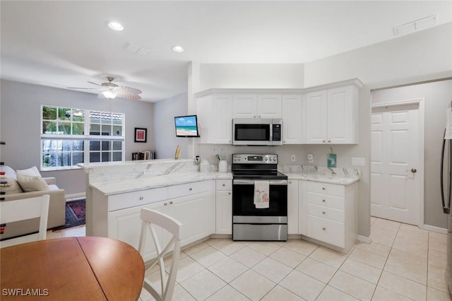 20101 Seagrove St Unit 702, Estero, FL 33928 - kitchen with stainless steel appliances, a peninsula, white cabinets, ceiling fan, and light tile patterned floors