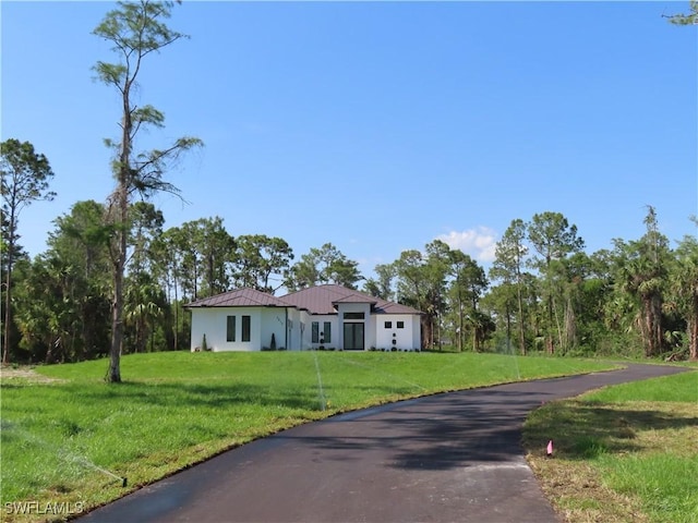 3813 16th Ave NE, Naples, FL 34120 - view of front of house featuring a front yard, metal roof, asphalt driveway, and stucco siding