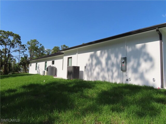 3813 16th Ave NE, Naples, FL 34120 - view of side of home featuring central air condition unit, stucco siding, and a lawn