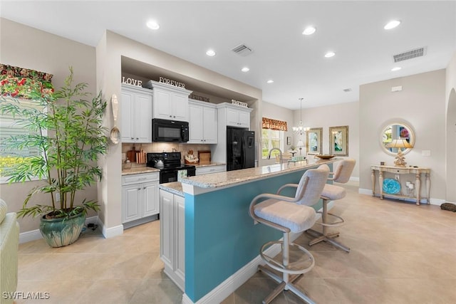 10450 Materita Dr, Fort Myers, FL 33913 - kitchen featuring black appliances, a breakfast bar, white cabinets, an island with sink, and tasteful backsplash
