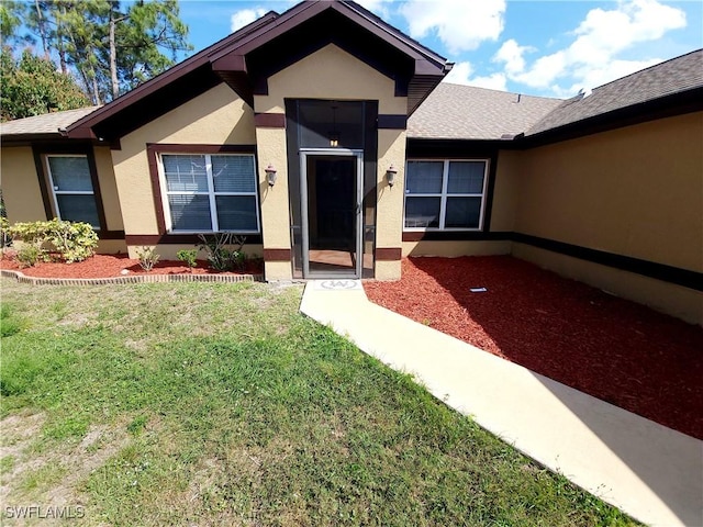 506 Desoto Ave, Lehigh Acres, FL 33972 - property entrance with stucco siding, a lawn, and a shingled roof