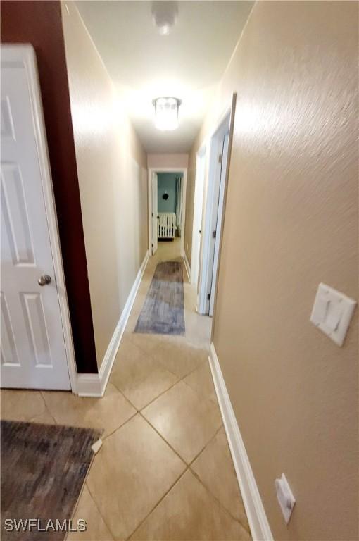 506 Desoto Ave, Lehigh Acres, FL 33972 - hallway with light tile patterned flooring, baseboards, and radiator heating unit