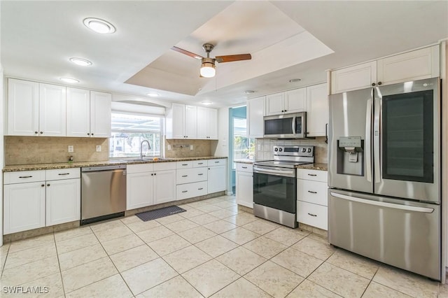 4330 S Canal Cir, North Fort Myers, FL 33903 - kitchen with appliances with stainless steel finishes, decorative backsplash, a tray ceiling, a sink, and white cabinets