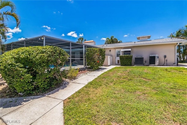 4330 S Canal Cir, North Fort Myers, FL 33903 - rear view of property featuring cooling unit, stucco siding, a yard, and glass enclosure
